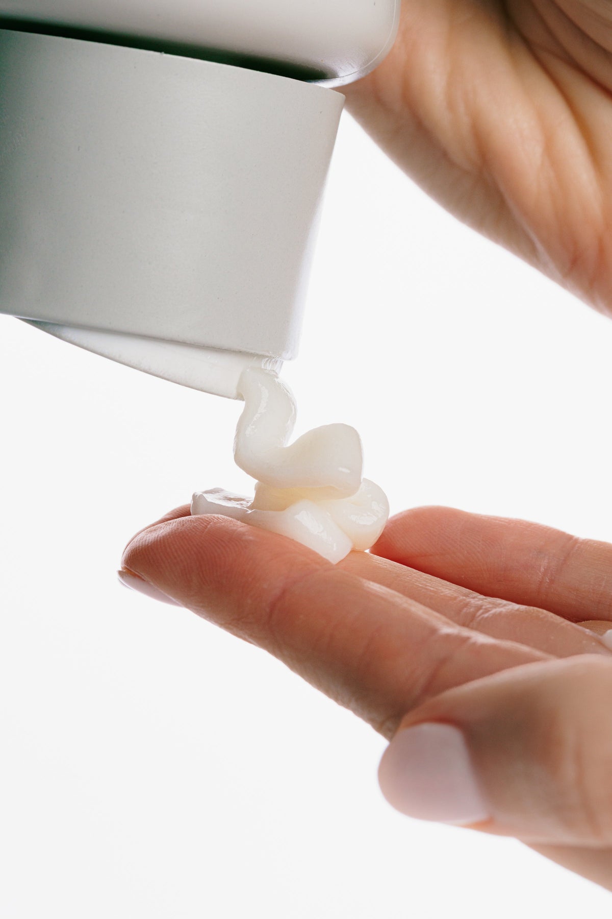 Witte crème wordt uit een tube op een vingertop geknepen