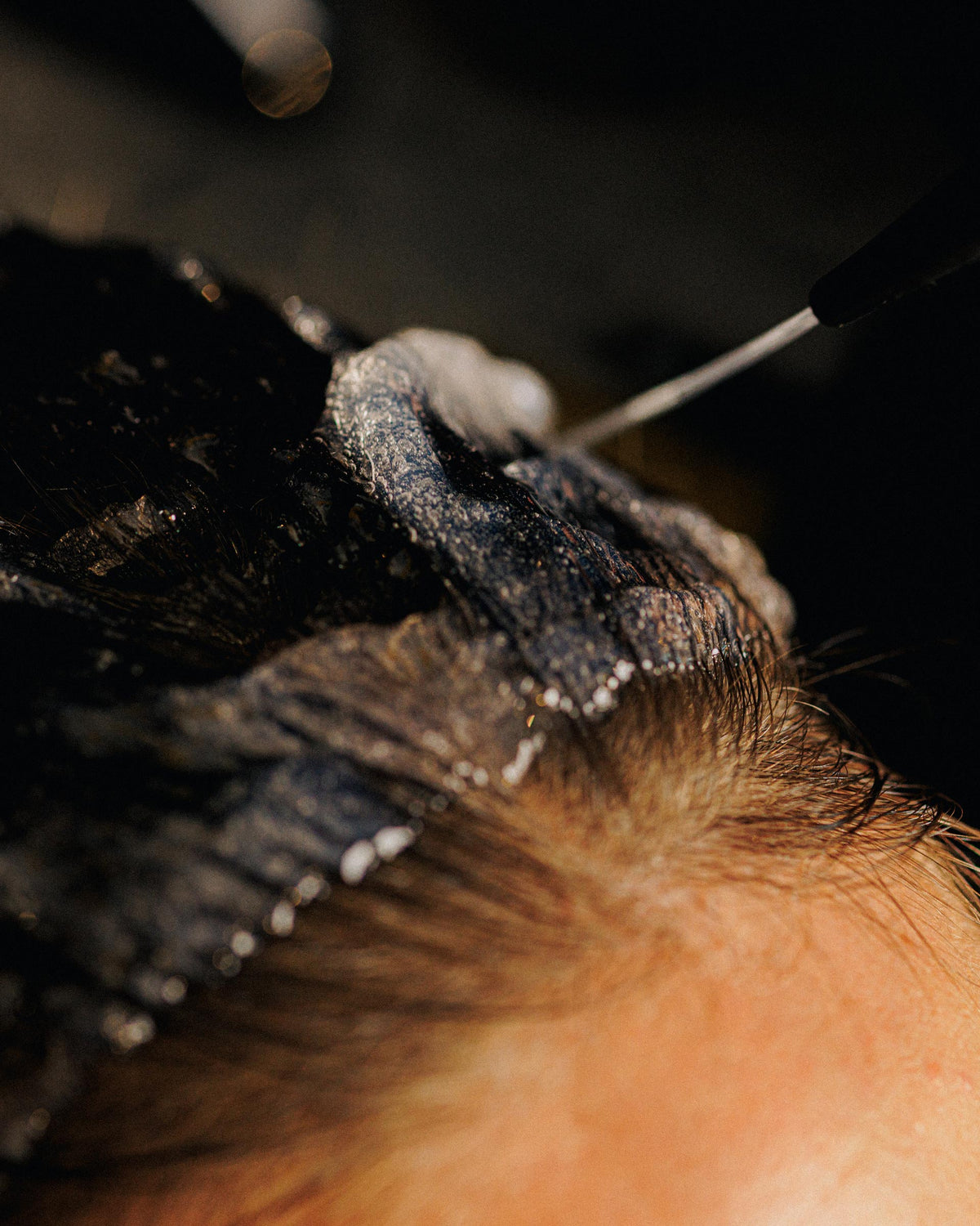 Treatment wordt met een fijne tuit op de haaraanzet van donker haar aangebracht